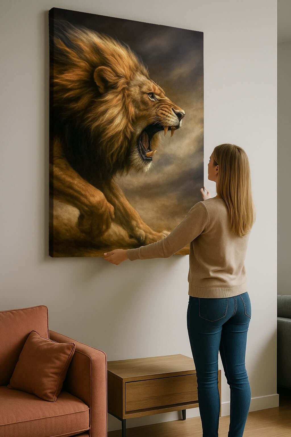 Canvas Schilderij woonkamer De Leeuw Ontwaakt, vrouw hangt groot schilderij met leeuw aan de muur in moderne ruimte.